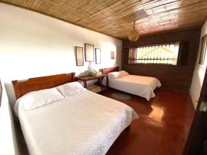 a bedroom with two beds and a table and a window at Finca Cafetera Madrigal - Café Sortiz in Maravélez
