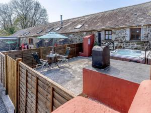 a patio with a tv and a table and a tub at 1 bed property in Brynteg 81354 in Llanwenog