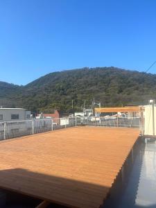 a large wooden deck with a mountain in the background at Hostel JAQ takamatsu in Takamatsu