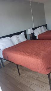 a bedroom with two beds with red sheets and white pillows at Motel 9 in Laredo