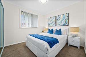 ein weißes Schlafzimmer mit einem großen Bett mit blauen Kissen in der Unterkunft Charming 2-Bed Moss Vale Getaway in Moss Vale