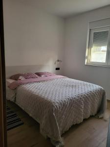 een slaapkamer met een bed met een witte sprei en een raam bij Holiday house with a swimming pool Ljubac, Zadar - 22537 in Krneša