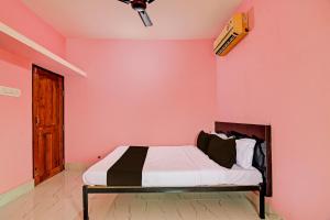 a bedroom with a bed in a pink wall at OYO MAA BHUASUNI RESIDENCY in Cuttack