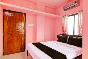 a pink bedroom with a bed and a wooden door at OYO MAA BHUASUNI RESIDENCY in Cuttack