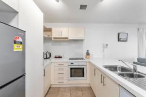 a white kitchen with white cabinets and a sink at Beach Views at Oceanside in Mount Maunganui