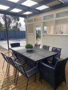 een houten tafel met stoelen en een potplant op een patio bij Kingston Beach Home - Beach & Bush Views in Kingston Beach