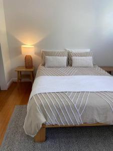 een slaapkamer met een groot bed en een lamp op een tafel bij Kingston Beach Home - Beach & Bush Views in Kingston Beach
