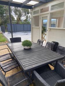 een houten tafel met stoelen en een potplant erop bij Kingston Beach Home - Beach & Bush Views in Kingston Beach