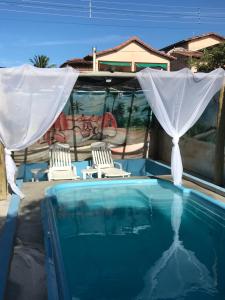 a swimming pool with two chairs and a canopy at Casa Temporada Frente à Praia Piscina Ar cond Nova Viçosa VA in Nova Viçosa