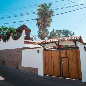 a house with a wooden gate and a tree at Hill House Mazatlan - Bed & Breakfast in Mazatlán