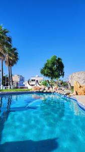 a swimming pool with blue water and palm trees at Hill House Mazatlan - Bed & Breakfast in Mazatlán