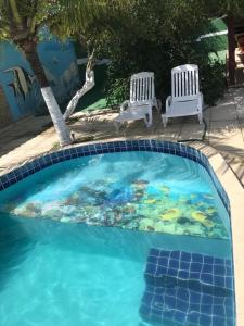 una piscina con una pintura junto a dos sillas en Casa Temporada Nova Viçosa 5 Quartos e Linda Piscina, en Nova Viçosa