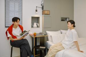 a man and a woman sitting on a bed in a room at Aank Hotel Sinchon in Seoul