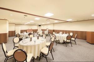 une salle de conférence avec des tables et des chaises blanches dans l'établissement Hirosaki Park Hotel, à Hirosaki