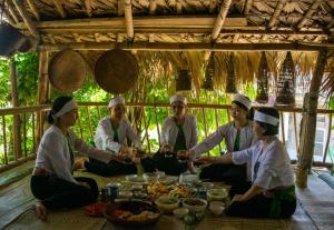 eine Gruppe von Menschen, die an einem Tisch mit Essen sitzen in der Unterkunft Homestay TonyLuận in Phú Thọ