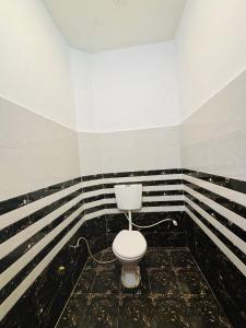 a bathroom with a toilet in a room with black and white stripes at Atithi Dev Guest House in Ayodhya