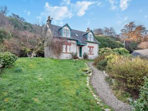 une maison blanche sur une colline avec une route en gravier dans l'établissement 2 Bed in Lochranza 77882, à Lochranza