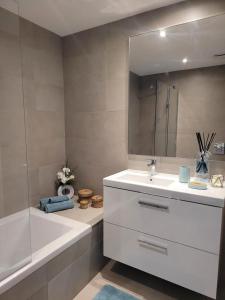 ein Badezimmer mit einem Waschbecken, einer Badewanne und einem Spiegel in der Unterkunft The Albufeira Concierge - Prime Sunset Design in Albufeira