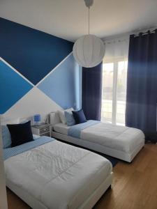 ein Schlafzimmer mit 2 Betten und einer blauen Wand in der Unterkunft The Albufeira Concierge - Prime Sunset Design in Albufeira