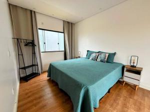 ein Schlafzimmer mit einem blauen Bett und einem Fenster in der Unterkunft CASA LIMA, nossa casa na represa in Itaí