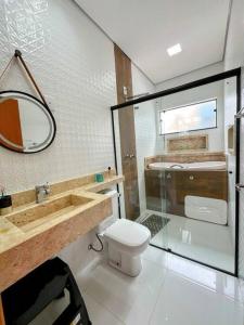 La salle de bains est pourvue de toilettes, d'un lavabo et d'un miroir. dans l'établissement CASA LIMA, nossa casa na represa, à Itaí
