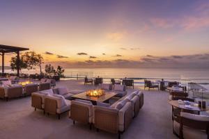 a restaurant with tables and chairs and a view of the ocean at Jumeirah Bali in Uluwatu