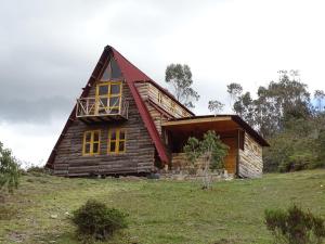 a log cabin with a red roof on a hill at La Teja Experience in Güicán