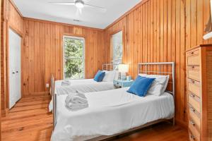 2 camas en una habitación con paredes de madera en Chasing Waves Luxury Edisto Home 3 mins to Beach en Edisto Island
