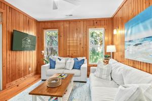 una sala de estar con paredes de madera y muebles blancos. en Chasing Waves Luxury Edisto Home 3 mins to Beach en Edisto Island