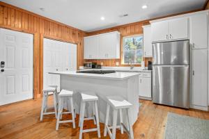 een keuken met witte kasten en een keukeneiland met krukken bij Chasing Waves Luxury Edisto Home 3 mins to Beach in Edisto Island