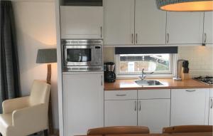 eine Küche mit weißen Schränken und einer Mikrowelle in der Unterkunft Chalet in Breukelen