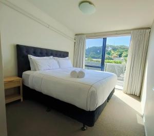 a bedroom with a large bed with a large window at Mount Stunner with King Beds in Mount Maunganui