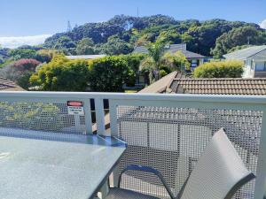 a glass table and a chair on a balcony at Mount Stunner with King Beds in Mount Maunganui