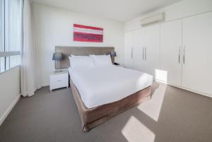 Oaks Nelson Bay Lure Suites في خليج نيلسون: غرفة نوم بيضاء مع سرير كبير ونافذة