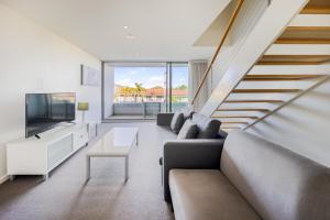 a living room with a couch and a tv at Oaks Nelson Bay Lure Suites in Nelson Bay