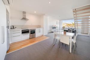 a kitchen with white cabinets and a table with chairs at Oaks Nelson Bay Lure Suites in Nelson Bay