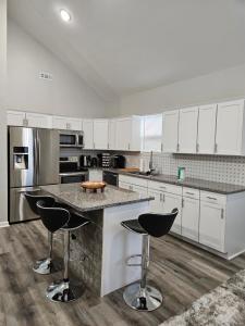una cocina con armarios blancos y una isla con taburetes. en New 3BD Home Near Downtown Indy, en Indianápolis