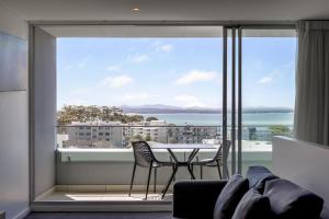 Cette chambre dispose d'une grande fenêtre et d'une table avec des chaises. dans l'établissement Oaks Nelson Bay Lure Suites, à Nelson Bay