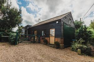 a small black house with a fence in front of it at The Carriage House a relaxing 1-Bed Cottage in Ash in Ash