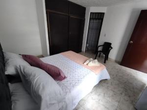 a bedroom with a large white bed with two pillows at lindo apartamento cerca ala Basílica buga in Buga
