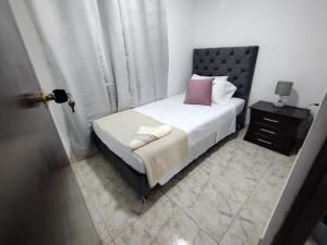a bedroom with a bed with white sheets and pink pillows at lindo apartamento cerca ala Basílica buga in Buga
