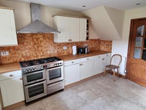 a kitchen with white cabinets and a stove top oven at Maryland Cottage Nr Gatwick in Godstone +16 photos