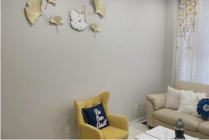 een woonkamer met een gele stoel en een klok aan de muur bij Luxury Room in Mississauga