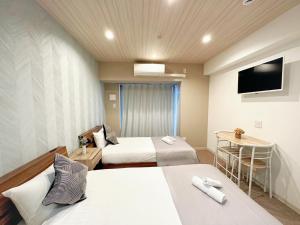 a hotel room with two beds and a flat screen tv at Hoshino Stay 1 in Osaka