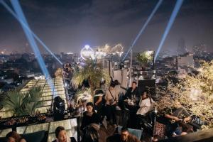 una multitud de personas sentadas en una azotea por la noche en La Mejor Hotel & Sky Bar en Hanói