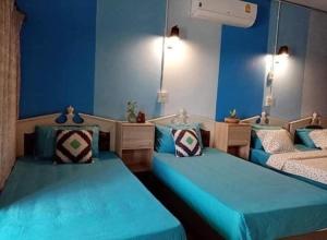 two beds in a room with blue walls at Saming Chiang Dao Guest House in Chiang Dao