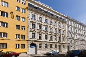 duży żółty budynek z samochodami zaparkowanymi przed nim w obiekcie Vienna Stay Apartments Castellez 1020 w Wiedniu