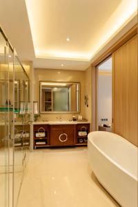 a bathroom with a large tub and a mirror at Hua Long Hotel Lancang in Lancang