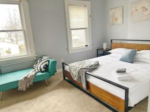een slaapkamer met een bed, een bank en 2 ramen bij The Columbus Den - Enjoy 3 BRs in the Upper Deck! in Columbus