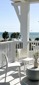 eine Veranda mit weißen Stühlen und dem Meer im Hintergrund in der Unterkunft The Taj Of The Gulf! Luxury Beach Mansion! Sleeps 37, private pool & hot tub, putting golf in Panama City Beach